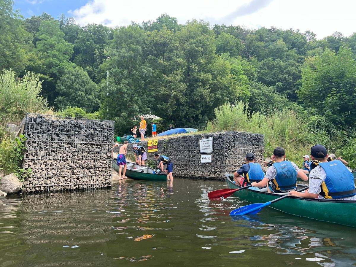 Kanugruppe mit Schwimmwesten beim Anlegen an einer Uferstelle